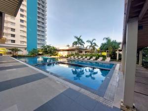 a swimming pool at a resort with chairs and buildings at Jade's Place Condo in Bacolod