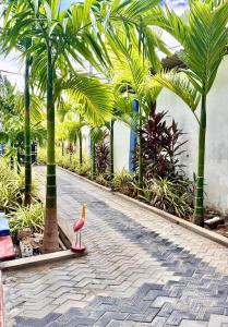 a pink flamingo standing on a brick road with palm trees at Oasis Wings Hotel in Mannar