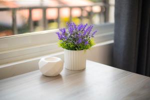 a white vase with purple flowers sitting on a table at EK Breeze Kalutara in Kalutara