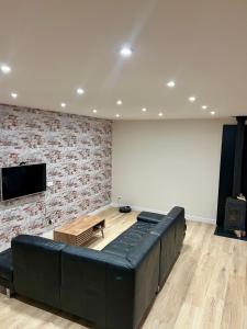 a living room with a black couch and a tv at Duplex spacieux-2chambres-ideal vehicule electrique in Melle