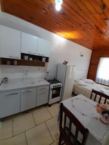 a kitchen with a refrigerator and a sink and a table at Pousada Tio Mica in Nova Petrópolis