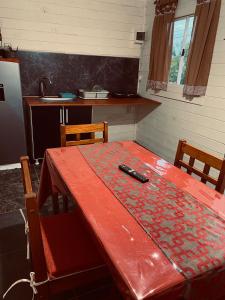 a kitchen with a red table with a remote control on it at Cabaña Valle de Montañas in Tinogasta