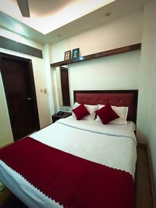 a bedroom with a large bed with red pillows at Hotel Parth Palace in New Delhi