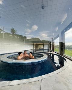 three people in a jacuzzi in a swimming pool at Lagamar Hotel Varginha in Varginha
