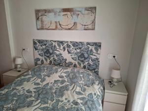a bedroom with a bed with a floral bedspread and two lamps at Casas Holiday - Playa la Mata Laredo in La Mata