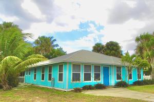 a blue house with palm trees in front of it at Pelican Cottage in Jensen Beach