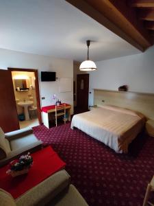 a hotel room with a large bed and a couch at Hotel Cime d'Auta in Falcade