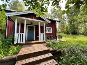 a red cabin with a wooden deck in the woods at Urlaub im Elchland in Letafors +16 photos