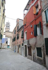 an alley with buildings and a clock tower in the distance at Caterina Biennale Apartment in Venice