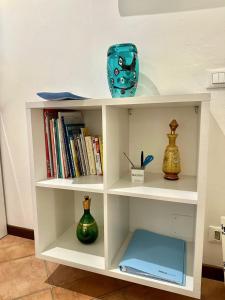 a white book shelf with books and vases on it at Caterina Biennale Apartment in Venice