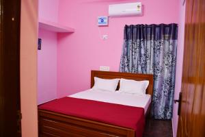 a small bedroom with pink walls and a bed at Srinivasam service apartment in Madurai