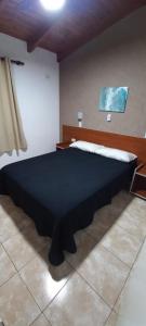 a bedroom with a large black bed in a room at LA TORRE - Complejo de cabañas in Villa Rumipal