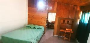 a bedroom with a green bed and a wooden wall at Dpto en Santa María de Punilla in Córdoba