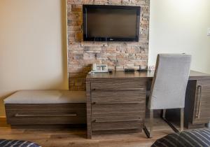 un bureau avec une chaise et une télévision sur un mur de briques dans l'établissement Complexe Hotelier Le 55, à Bécancour