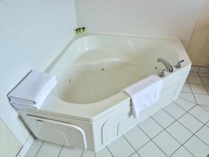 a white bath tub in a white tiled bathroom at Continental Inn & Suites in Edmonton +48 photos