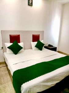 a large white bed with green and red pillows at Hotel Parth Palace in New Delhi
