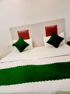 a white bed with green and red pillows on it at Hotel Parth Palace in New Delhi +4 photos