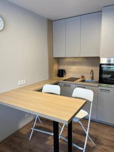 a kitchen with a wooden table and two white chairs at Гнёздышко in Visaginas
