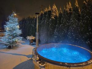 a hot tub in the snow with a christmas tree at Chatki ŁoRawa w Jabłonce in Jabłonka