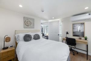a bedroom with a large white bed and a desk at Private 3BR Home - Hot Tub, Yard, Arcade & Parking in Simi Valley