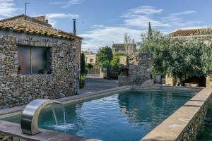 a swimming pool in front of a house with a fountain at Can Barrull-Costa Brava-Emporda in San Felíu de Boada