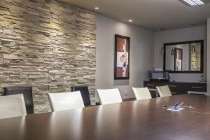 une salle de conférence avec une table en bois et des chaises blanches dans l'établissement Complexe Hotelier Le 55, à Bécancour