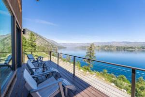 a balcony with blue chairs and a view of a lake at Constellations Lake House at Chelan - Pacific Retreats in Chelan