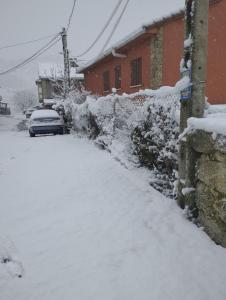a snow covered driveway with a car parked next to a house at Winahost Casita Sierra de Madrid in Las Herreras