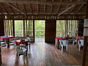 a dining room with tables and chairs on a wooden floor at Las Cabañas del Rio in Minca