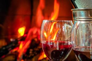 two glasses of red wine next to a fireplace at VELINN Pousada Locanda Belvedere in Monte Verde