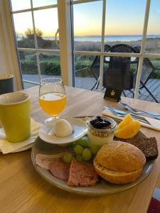 a plate of food with eggs and bread and a glass of orange juice at Gammel Løgten Strandkro in Hornslet