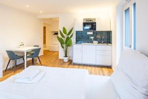 a white bedroom with a kitchen and a table at Montelio Living in Ettlingen