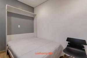 a bedroom with a white bed and a black chair at Apartamento no tradicional Bairro do Bixiga em SP in São Paulo +20 photos