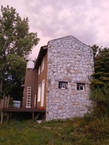 a stone house with a ladder on the side of it at Cabaña Kokopelli in Villa Giardino