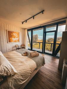 a bedroom with a large bed and large windows at Bed & Breakfast Casa Ziré in Navidad