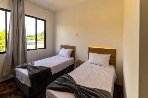 two beds in a room with a window at Ibirama Vale Hotel in Ibirama