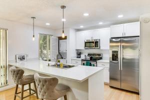 a kitchen with white cabinets and a stainless steel refrigerator at Condo in PGA National Resort w/ Pool & Spa! in Palm Beach Gardens