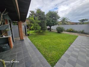 a backyard with a lawn and a fence at Família Marques in Itanhaém