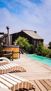 a wooden deck with chairs next to a swimming pool at Bed & Breakfast Casa Ziré in Navidad
