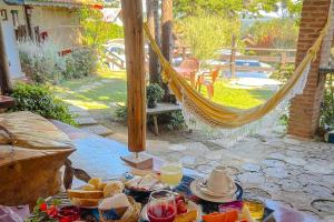 a table with food and a hammock on a patio at VELINN Pousada Locanda Belvedere in Monte Verde