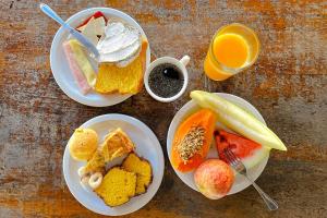 a table with three plates of food and a glass of orange juice at VELINN Pousada Locanda Belvedere in Monte Verde