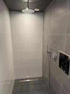 a bathroom with a shower with a tile wall at BenB Tuskendepade in Oldeholtpade +6 photos