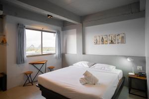 a bedroom with a bed with white sheets and a window at THT by Thai Hotel Krabi in Krabi