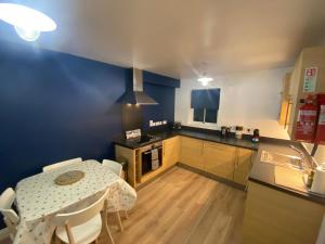 a kitchen with a table and a kitchen with blue walls at Seaglass, The Bay - Filey Ground Floor Step Free Easy Access and Parking in Filey
