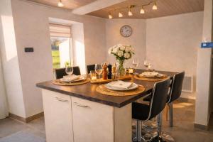 a dining room table with chairs and a clock on the wall at Au Chant des Roches Gîte en pierre avec jardin à Cerfontaine in Cerfontaine