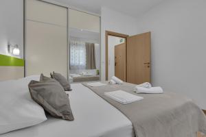 a white bedroom with two beds and a mirror at Apartmani Podest II in Baška Voda +103 photos