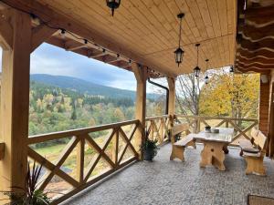 a porch with a table and benches and a view at Górska Chata w Górach Bystrzyckich in Niemojów