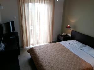 a bedroom with a bed and a television and a window at Tokalis Boutique Hotel & Spa in Nea Anchialos