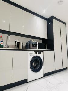 a washing machine in a kitchen with white cabinets at Large Double Bed En-suite Room 20 mins from Heathrow in Burnham