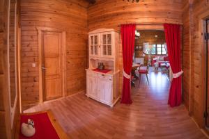 a kitchen in a log cabin with red curtains at Hirsch Chalet in Bömighausen